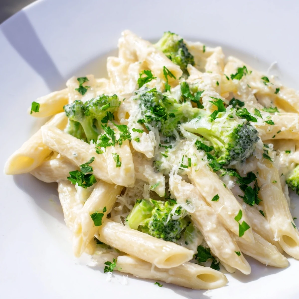 A close-up shot of rich cream cheese garlic pasta, garnished with fresh parsley and Parmesan.