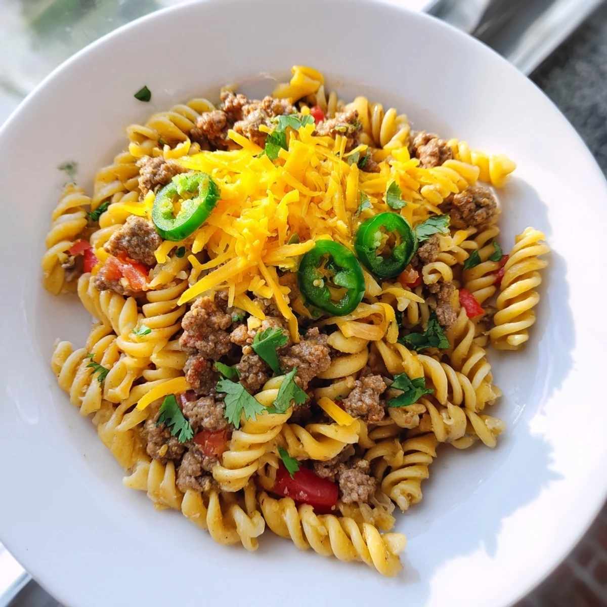 A close-up of a bubbling Beef Taco Pasta Skillet showcasing the creamy cheese and savory beef.