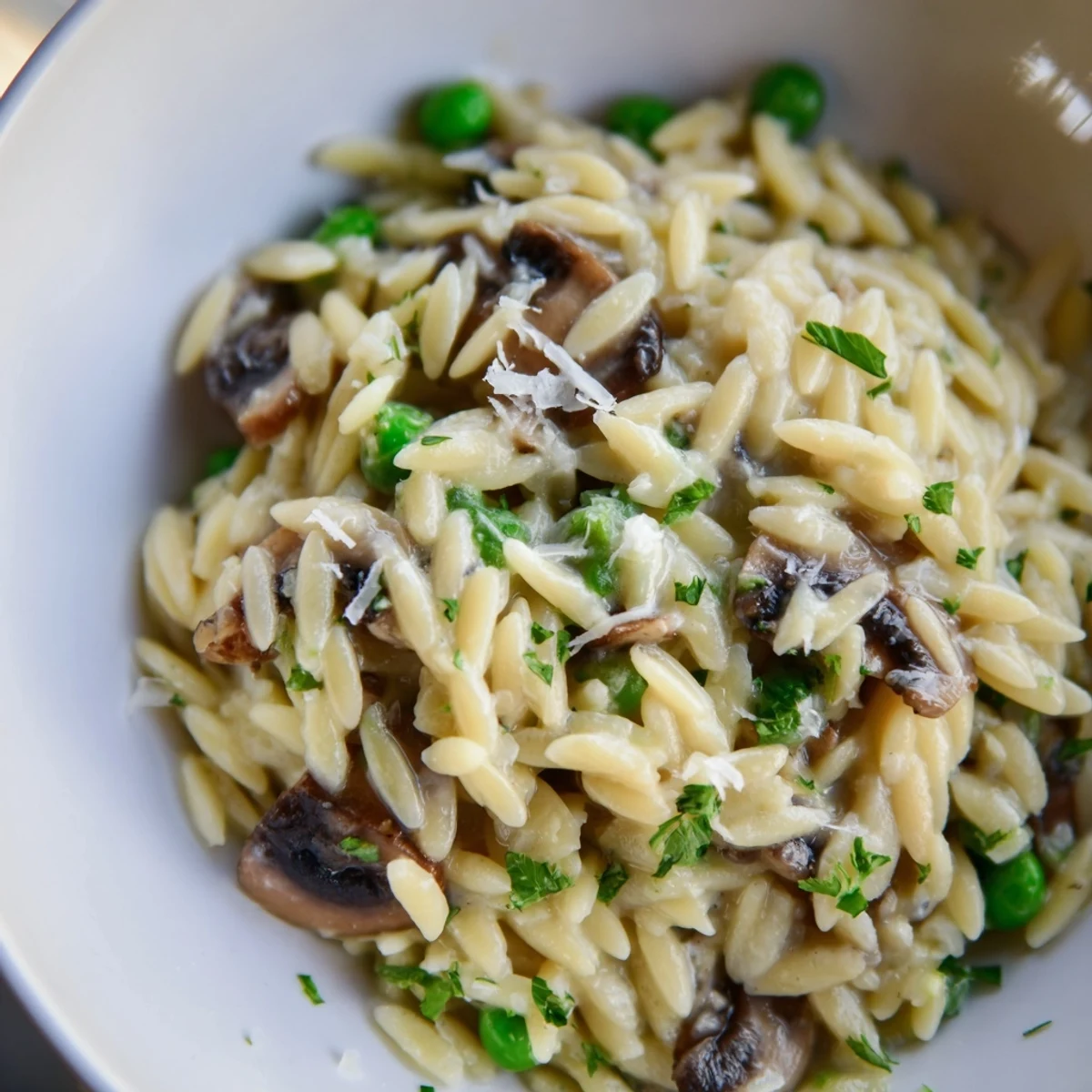 Creamy Orzo Mushroom Risotto-Style pasta with sautéed mushrooms and melted Parmesan, served steaming in a rustic bowl.  