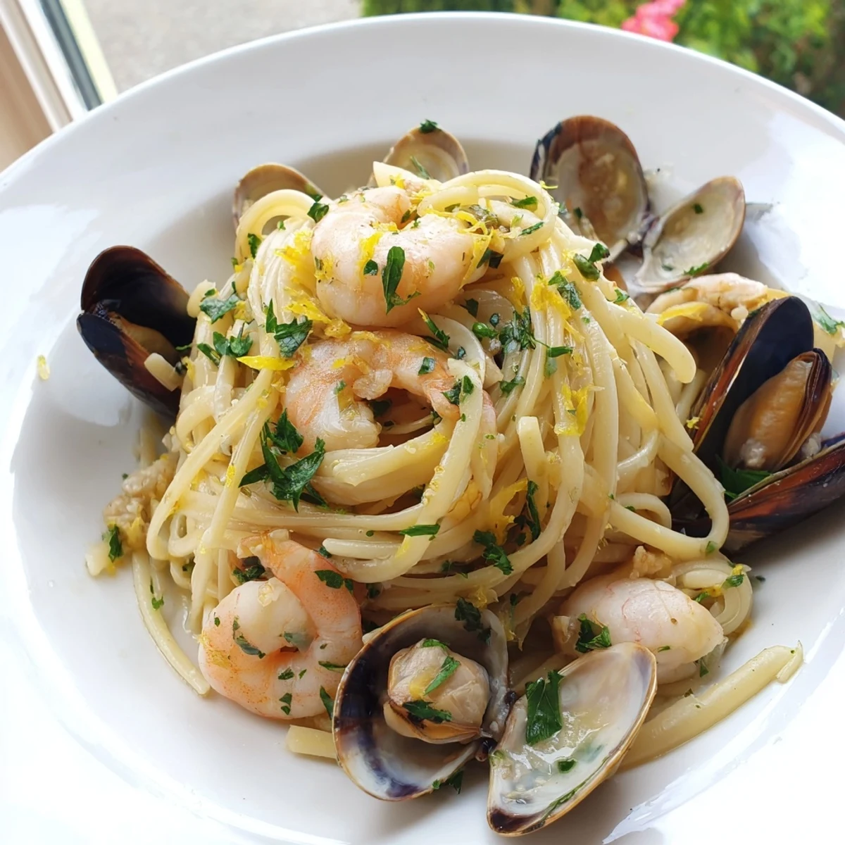 Steaming bowl of Seafood Linguine with plump shrimp, clams, and mussels coated in a bright garlic lemon sauce.