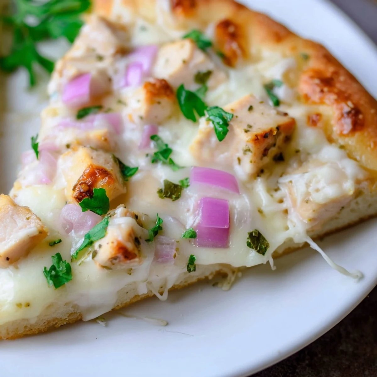 Golden-brown Chicken Alfredo Pizza on a wooden board, topped with creamy sauce, diced chicken, and melted mozzarella.