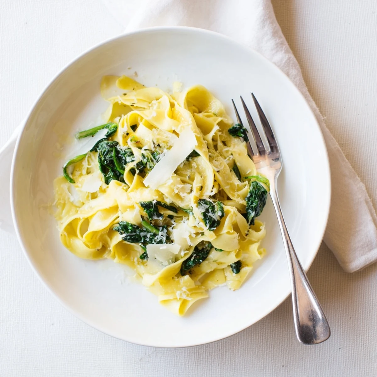A skillet of Creamy Spinach Garlic Noodles, garnished with red pepper flakes and herbs, ready to serve for dinner.