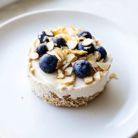 These no-bake protein cheesecake cups showcase a creamy filling over a crunchy, sweet base.