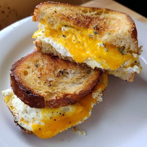 Mouthwatering close-up of a feta fried eggs grilled cheese, offering a warm, satisfying bite on your plate.