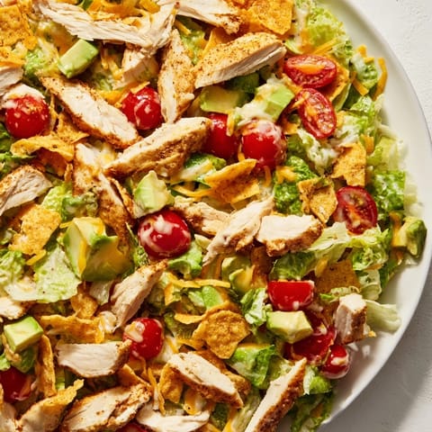 Freshly crushed taco shell pieces add texture to this vibrant Crunchy Taco Chicken Salad, topped with avocado and cherry tomatoes.  
