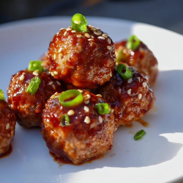 Close-up of deliciously glistening Spicy Sriracha Honey Meatballs, tossed in sweet and fiery glaze.