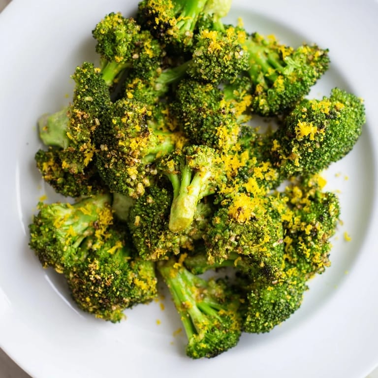 A close-up view displays perfectly roasted Lemon Garlic Roasted Broccoli, sprinkled with zesty lemon.