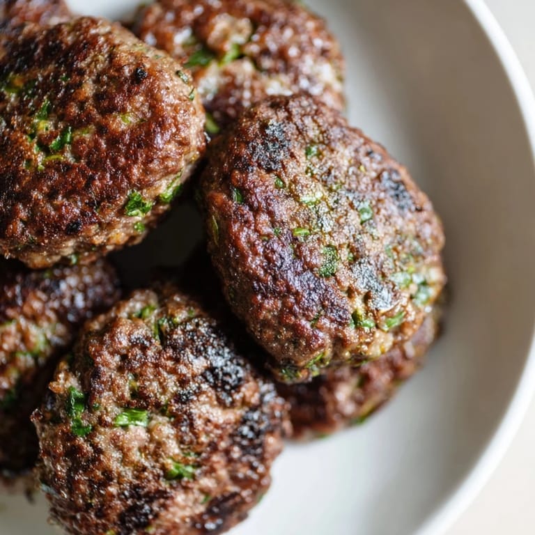 A plate of flavorful Turkish Köfte meatballs, sizzling hot and ready to enjoy with a side of flatbread.