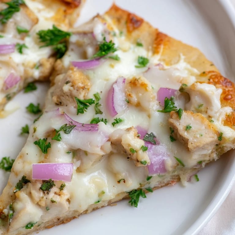 Freshly baked Chicken Alfredo Pizza on a baking sheet, featuring a golden crust, rich Alfredo sauce, and a blend of Italian cheeses.