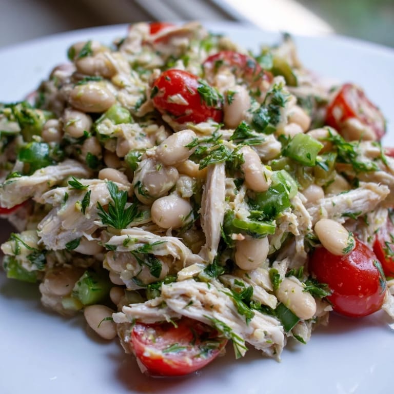 Close-up photo of Lemony White Bean Chicken Salad showing juicy cherry tomatoes, crisp celery, and bright parsley and dill tossed with white beans and shredded chicken.