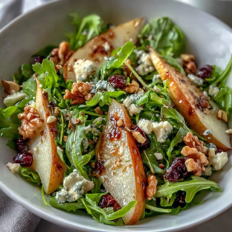 A vibrant Arugula and Pear Bowl tossed with balsamic dressing, served on a white plate for a healthy vegetarian lunch.