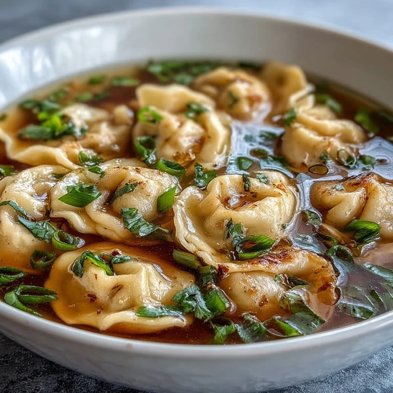 Warm bowl of Asian-inspired dumpling soup with scallions and rich chicken broth.  